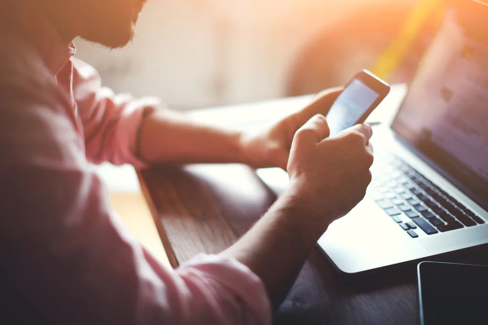 Mann mit Smartphone und Laptop